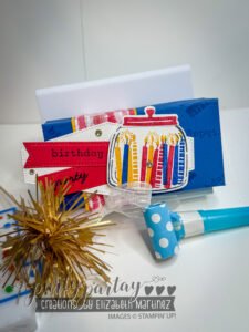 Mini birthday gift box decorated in Regal colors with gold shimmer, filled with ribbon, treats, and a noisemaker.
