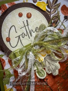 Zoomed view of layered frayed ribbon bow with die-cut leaves, gold embossing, and banner flags.