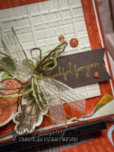 Detailed shot of embossed background with distressed designer paper, deconstructed linen thread, and leaf die cuts.